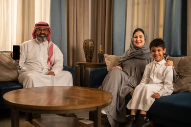 Saudi Family Sitting in Living Room Holding Smartphone