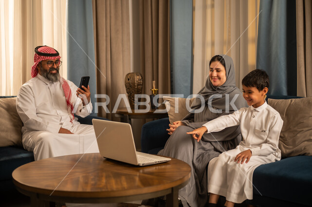 عائلة سعودية تستخدم الكمبيوتر المحمول والهاتف في المنزل