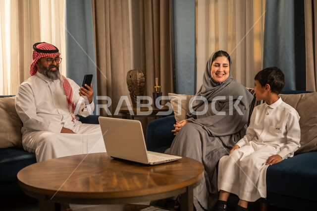 عائلة سعودية تستخدم الكمبيوتر والمحمول في غرفة المعيشة