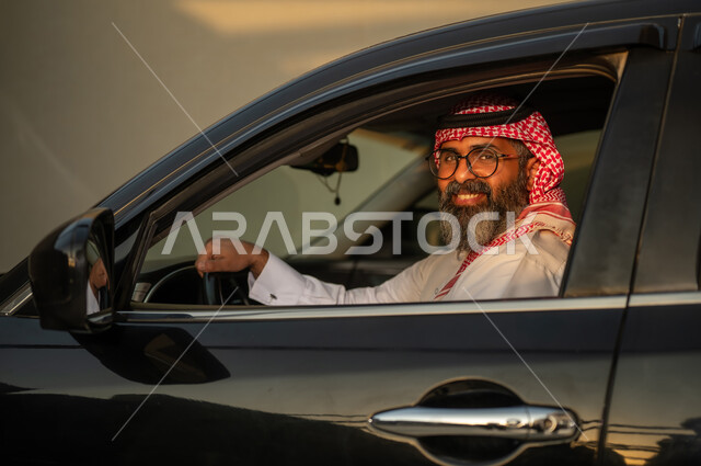 رجل سعودي بالزي التقليدي يقود سيارة وقت الغروب