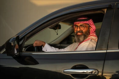 رجل سعودي بالزي التقليدي يقود سيارة وقت الغروب