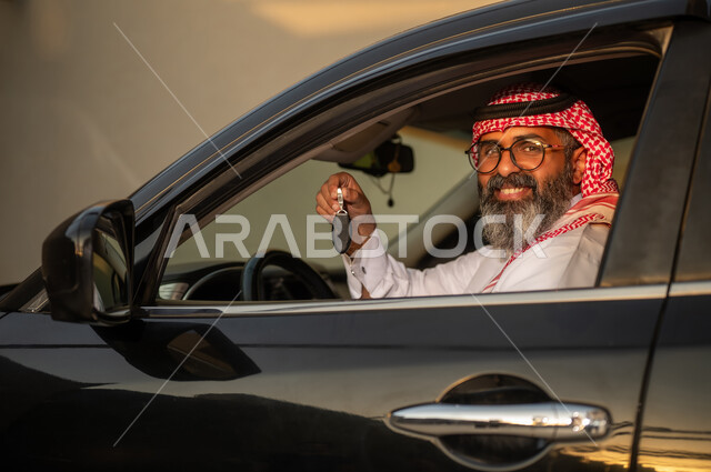 رجل سعودي يحمل مفتاح سيارة داخل مركبة وقت الغروب