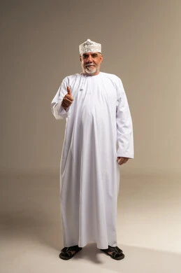 رجل عماني يرفع إبهامه بالزي التقليدي العماني