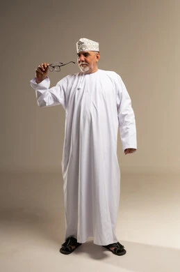رجل عماني مسن بالزي التقليدي يحمل نظارة طبية