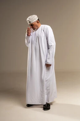 Omani Man in Traditional Dishdasha Drinking Water