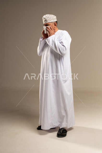 Omani Man Sneezing into Tissue in Traditional Dress