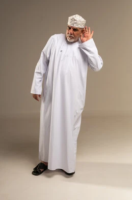 رجل عماني مسن بالزي التقليدي في وضعية الإنصات