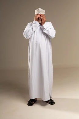 رجل عُماني مسن يغطي عينيه في الاستوديو