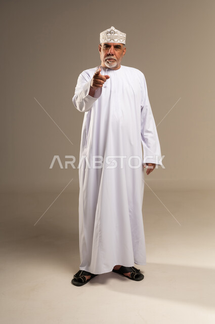 Senior Omani Man Pointing in Traditional Attire