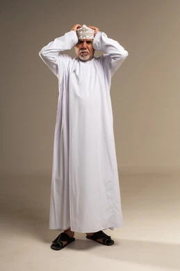 رجل عماني مسن بالزي التقليدي يضع يديه على رأسه