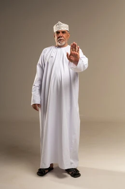 رجل عُماني بالزي التقليدي يشير بالتوقف