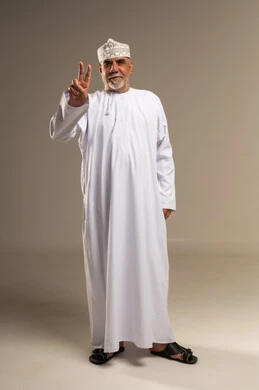 رجل عُماني بزي تقليدي يشير بعلامة النصر في استوديو