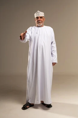 رجل عماني مسن يمد يده للمصافحة بالزي التقليدي