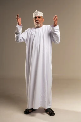 رجل عماني مسن يصلي باللباس التقليدي العماني