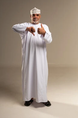 رجل عماني يرتدي الزي التقليدي بإيماءات الإبهام المختلفة