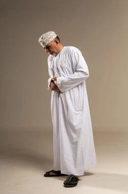رجل عماني بالدشداشة والكمة في وضعية الصلاة