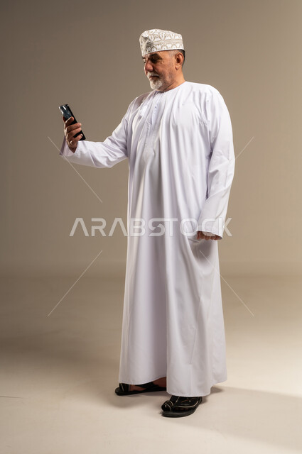 Omani Senior Man Using Smartphone in Studio