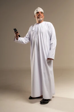 رجل عماني مسن بالزي التقليدي يحمل هاتف ذكي