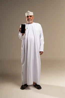 رجل عماني مسن يحمل هاتف ذكي في الاستوديو