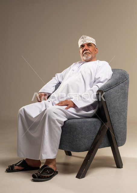 رجل عماني بالزي التقليدي يجلس على كرسي