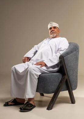رجل عماني بالزي التقليدي يجلس على كرسي