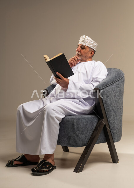 رجل عماني كبير السن يقرأ كتابا في استوديو