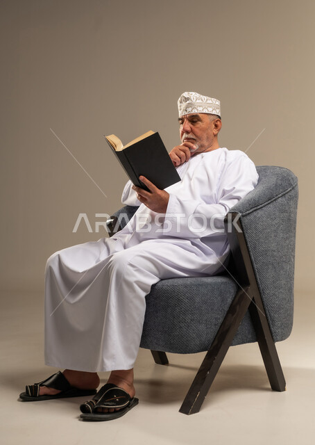 رجل عماني يقرأ كتاباً بالزي التقليدي العماني