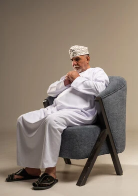 رجل عُماني مسن بالزي التقليدي يجلس في الاستوديو