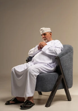 رجل عُماني مسن يجلس بالزي التقليدي في استوديو