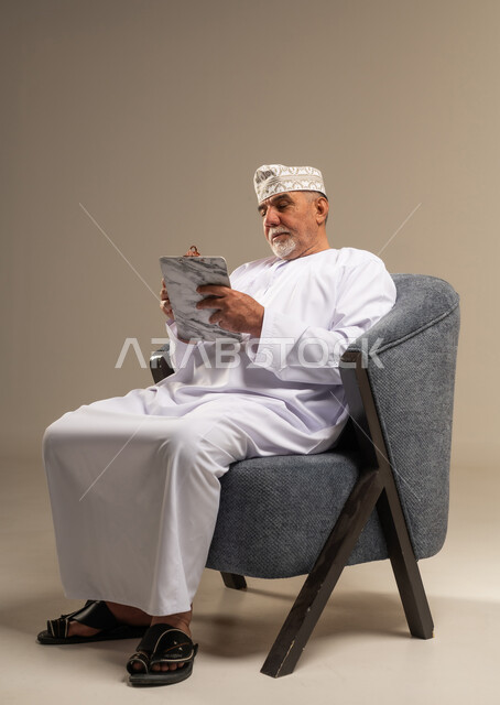 رجل عُماني مسن يكتب على جهاز لوحي في الاستوديو
