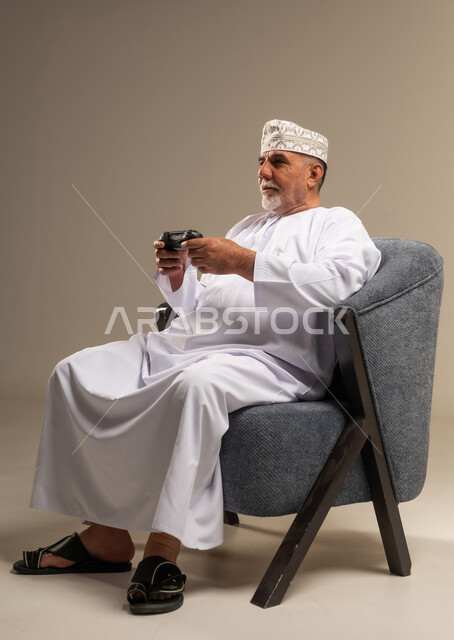 رجل عماني مسن يلعب ألعاب الفيديو في الاستوديو