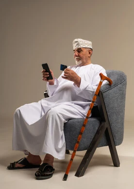 رجل عُماني مسن يستخدم الهاتف والبطاقة الائتمانية