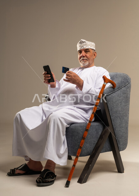رجل عماني مسن يستخدم هاتف ذكي وبطاقة ائتمان