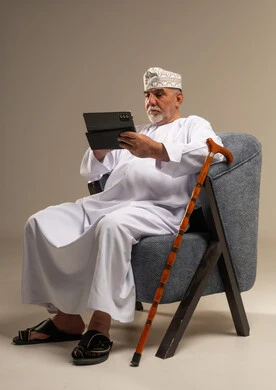 رجل عُماني مسن يستخدم جهازاً لوحياً في الاستوديو