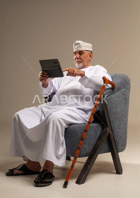 Elderly Omani Man Using Digital Tablet in Studio