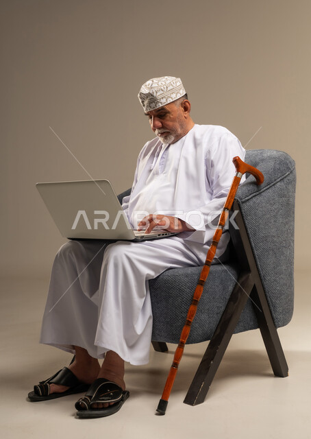 Elderly Omani Man Using Laptop in Studio