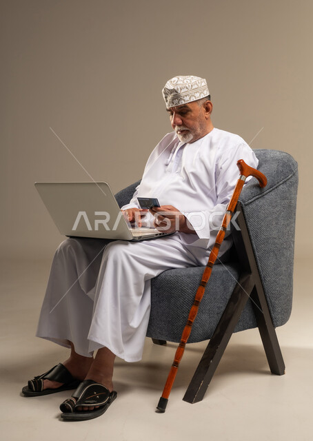 رجل عماني مسن يستخدم المحمول وبطاقة الائتمان