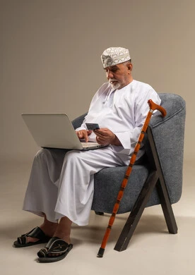 رجل عماني مسن يستخدم المحمول وبطاقة الائتمان