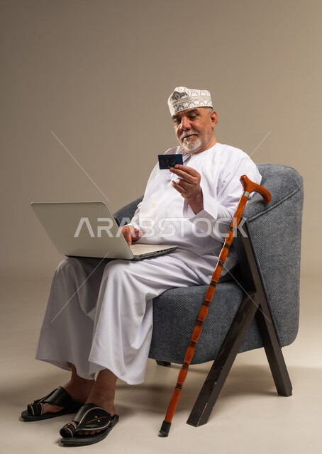 رجل عماني مسن يستخدم المحمول وبطاقة البنك