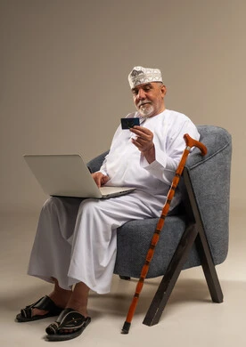 Elderly Omani Man Using Laptop and Credit Card