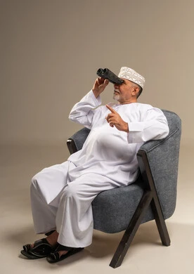 رجل عماني مسن يستخدم المنظار في الاستوديو