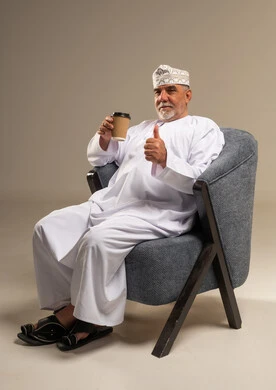 رجل عُماني بالزي التقليدي يحمل كوب قهوة