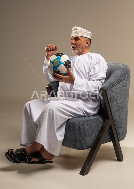 رجل عماني بالزي التقليدي يشجع بكرة القدم