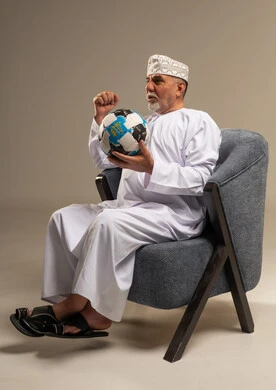 رجل عماني بالزي التقليدي يشجع بكرة القدم
