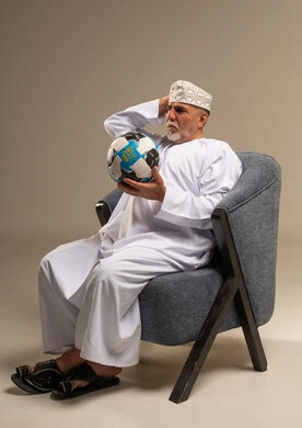 رجل عماني مسن مع كرة قدم في الاستوديو