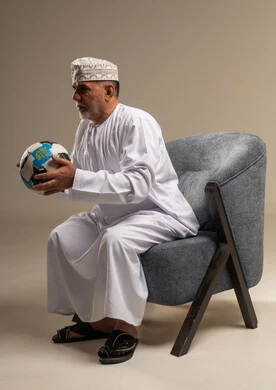 رجل عُماني بالزي التقليدي يمسك كرة قدم