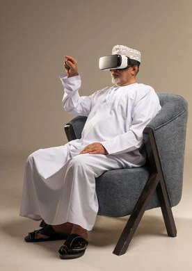 Omani Senior Man Wearing VR Headset Sitting in Armchair