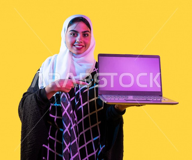 بورتريه لمرأة خليجية سعودية ، إستخدام جهاز الحاسوب المحمول ، عرض شاشة اللابتوب ، إستخدام أجهزة تقنية حديثة ، جلسة عمل ، تصفح الإنترنت ، عرض خدمات وتطبيقات عبر اللابتوب، التسويق الرقمي الإلكتروني ، مفهوم الإعلانات، خلفية صفراء