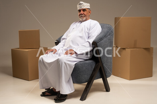Elderly Omani Man Sitting with Cardboard Boxes