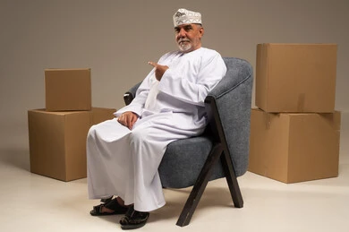 رجل عماني يشير إلى صناديق كرتونية في الاستوديو